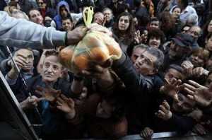 People reach out to take fruits and vegetables distributed for free by farmers during a protest against high production costs outside the Agriculture Ministry in Athens